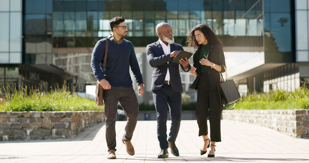 Walking compliance workers talking over iPad outside of office