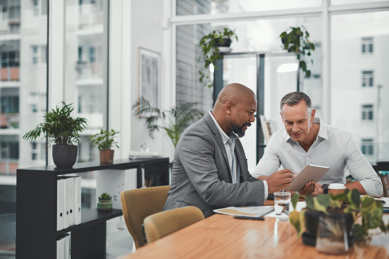 Two financial workers sitting at desk looking at tablet