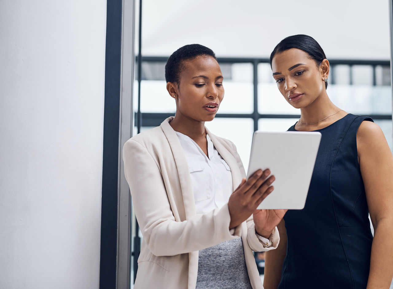 Shot of two businesswomen using a digital tablet together in a modern office