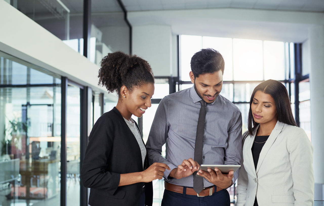 Shot of a group of business people using a digital tablet together in an office