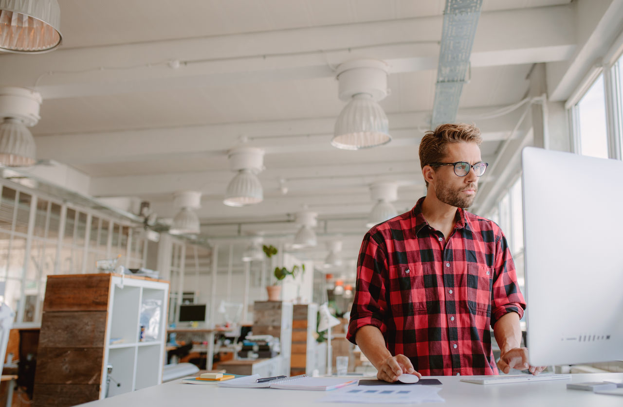 Young businessman in casual clothes at modern startup business office space, working on desktop computer.