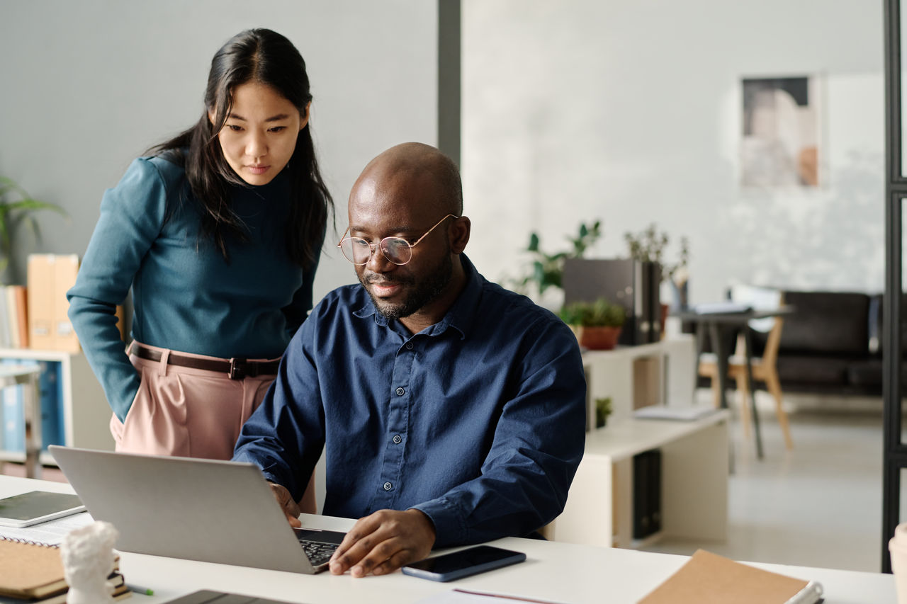 Man and woman working on laptop in office