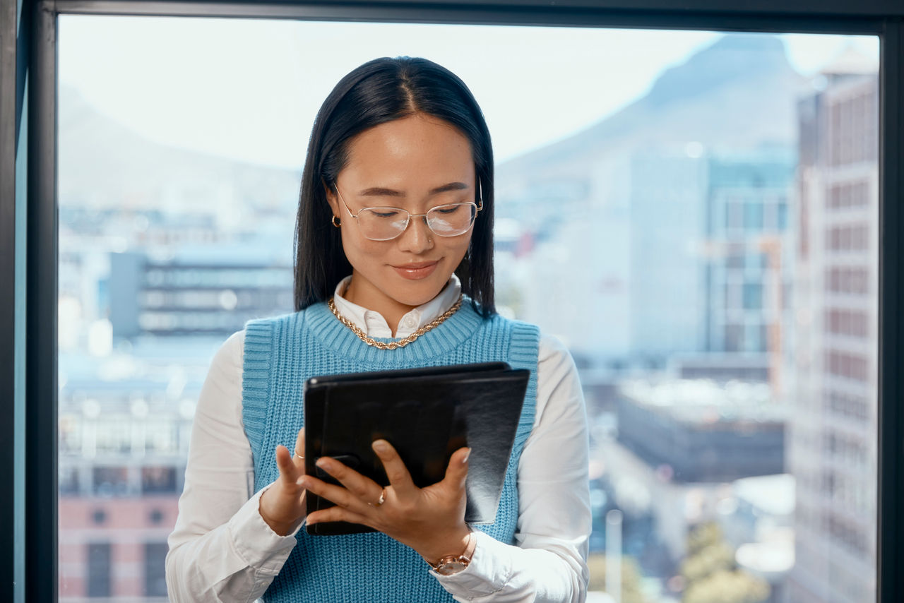 Woman in glasses staring at tablet happy in office