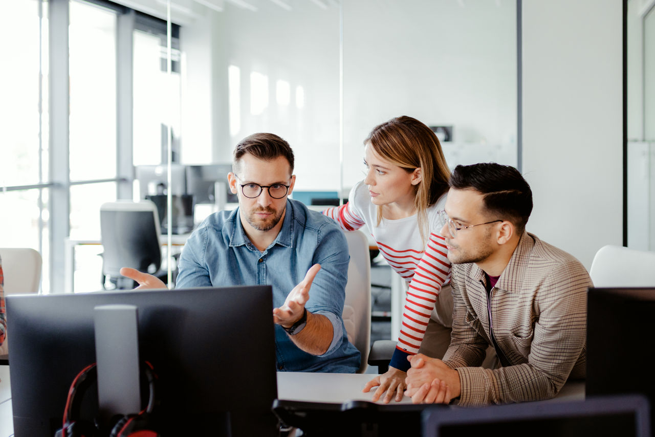 Team of programmers brainstorming around computer