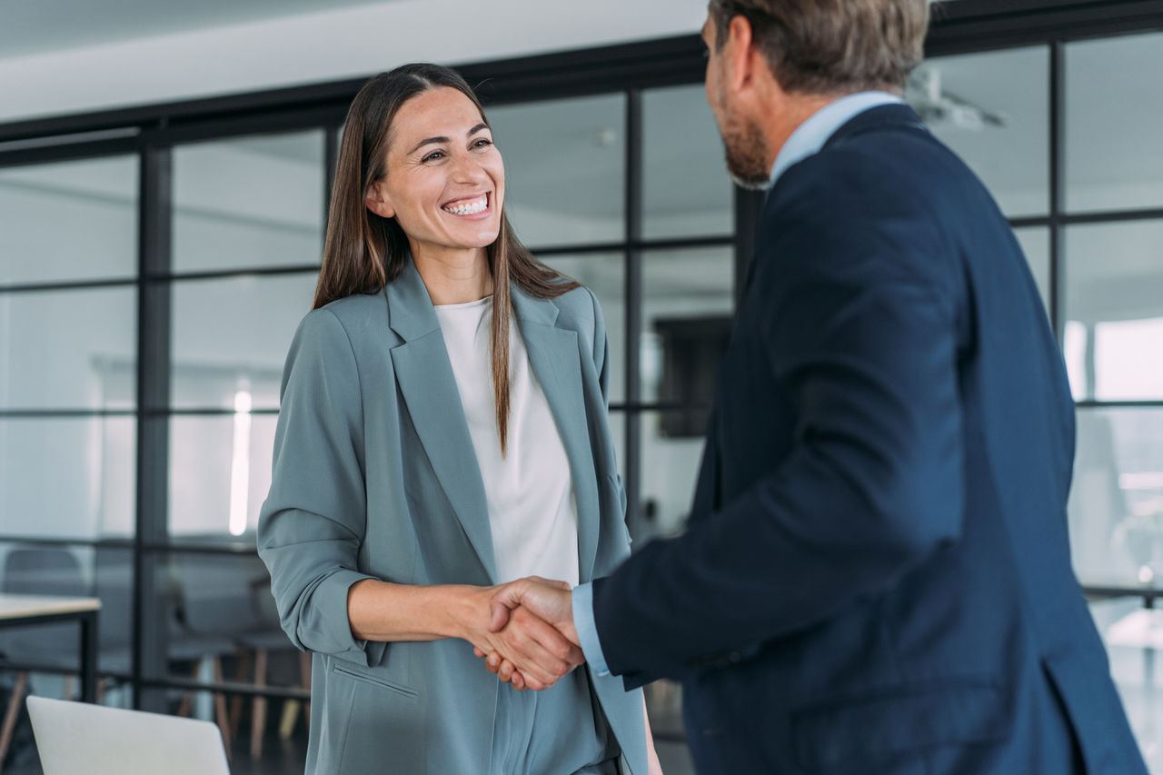 Business people shaking hands in modern office. 
