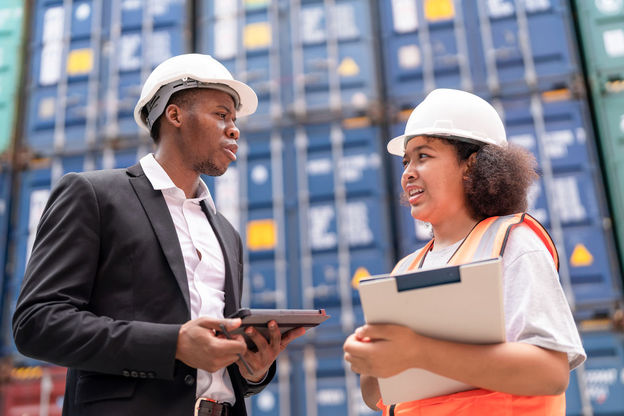 Dock manager standing and discussed over a tablet with engineer worker in shipment yard
