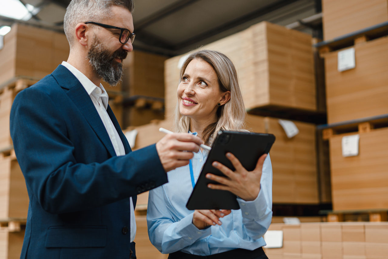 Two business people looking at tablet in warehouse