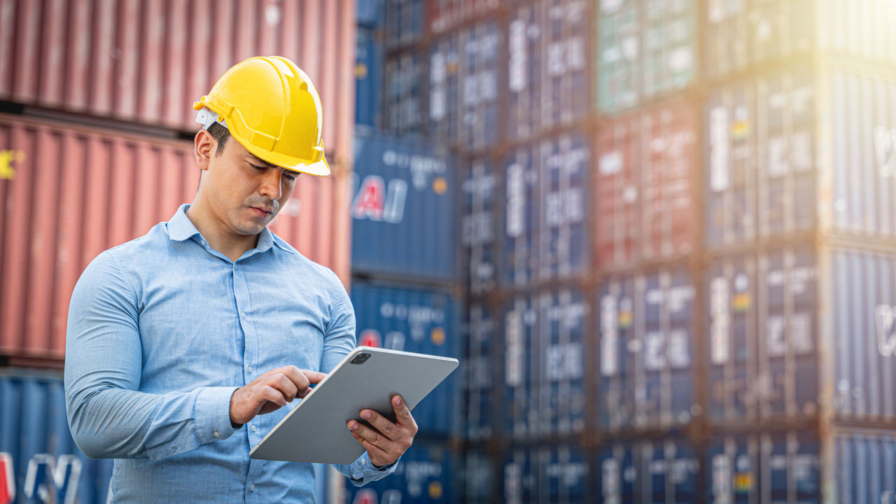 Business man looking at tablet in shipping container yard