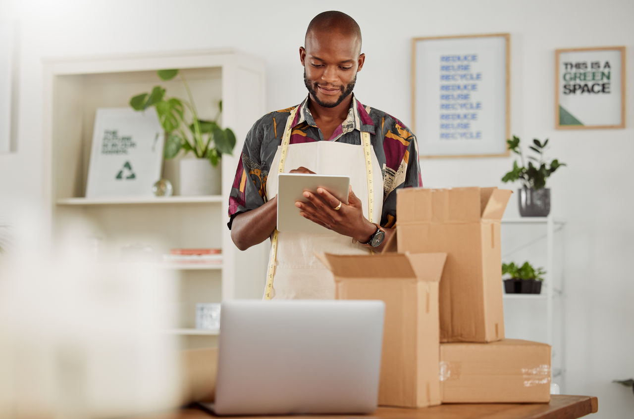 Small business owner or creative startup entrepreneur checking an online order. Fashion, style and design with a trendy designer and tailor working on a tablet in his textile workshop or studio.