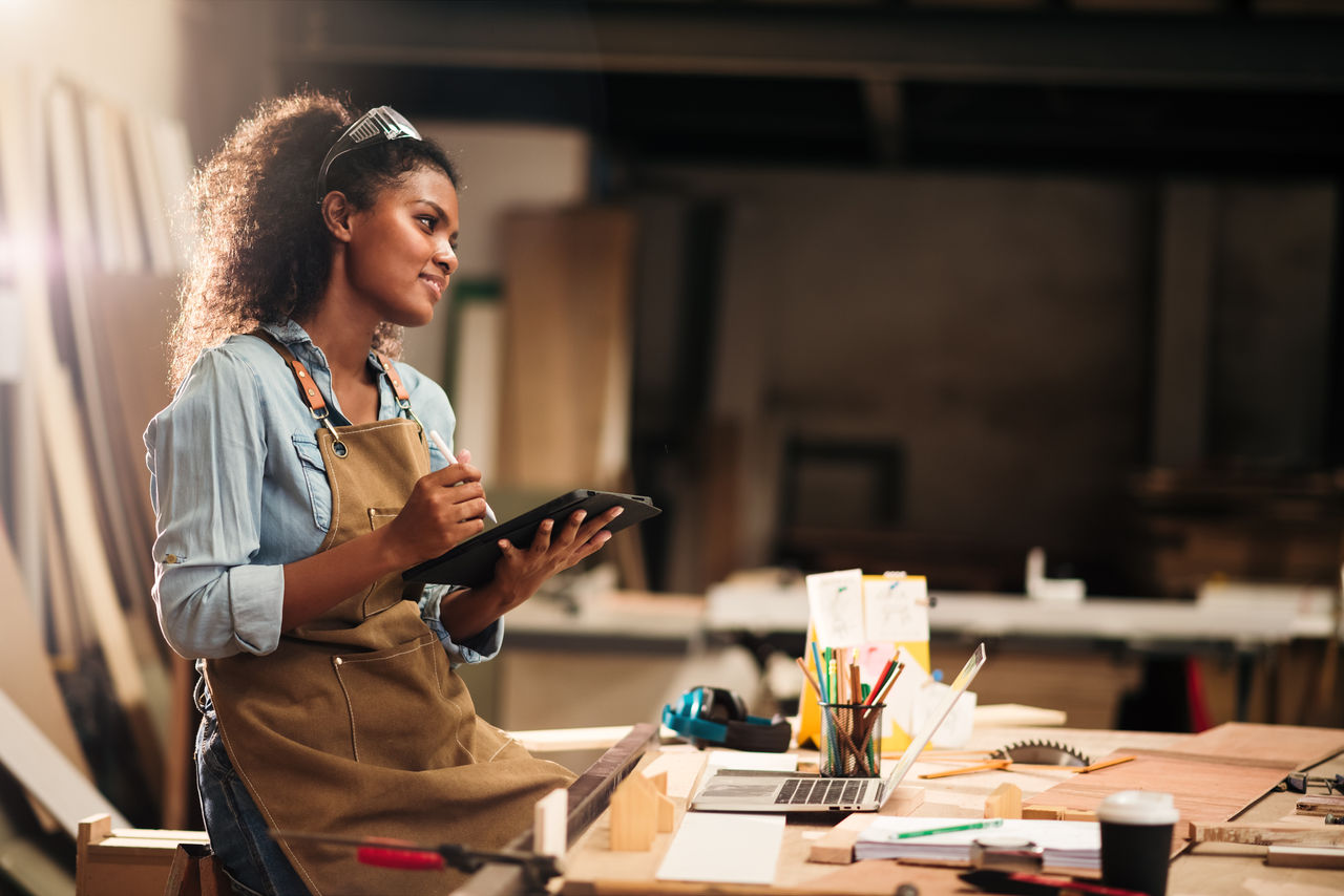 Young attractive african american female carpenter in wood working in small business workshop. Wood  industry and furniture industrial.