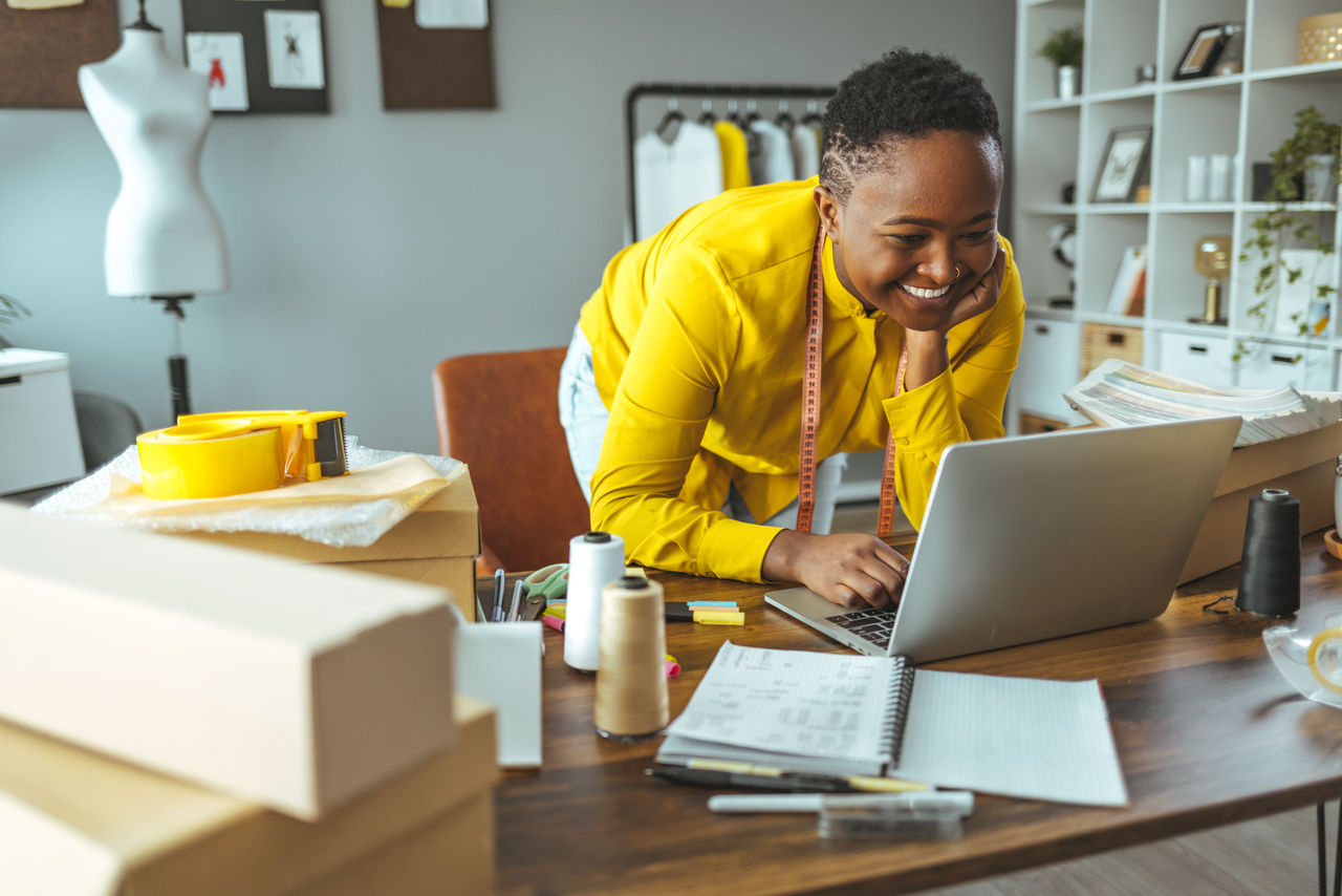 Small business owner woman works on a laptop in her large home office.